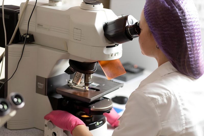 Лаборант дивиться у мікроскоп